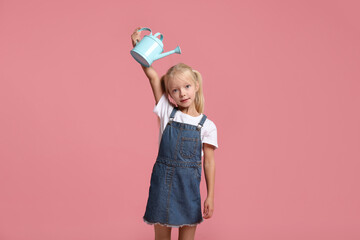 Little girl with watering can on pink background