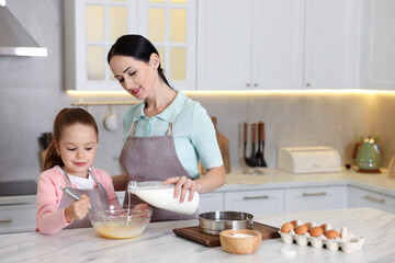 Little helper. Mother and daughter cooking together at white marble table in kitchen, space for text