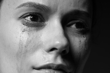 Fototapeta premium Sad woman crying on dark background, closeup. Black and white effect