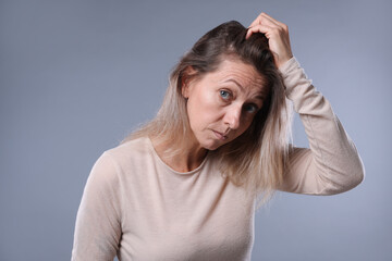 Worried woman with hair loss problem on grey background