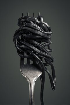Dramatic black squid ink pasta on silver fork presents modern gourmet closeup in studio lighting for culinary arts and innovative food presentation