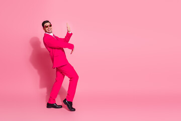 Bright stylish man in pink suit celebrating energetically against vibrant pink background depicting modern fashion trends