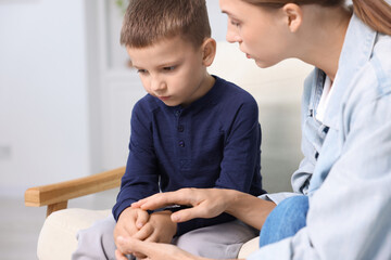 Obraz premium Mother supporting and holding hands with her upset son at home, closeup
