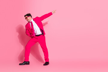 Stylish man in pink suit striking a fun pose on pastel pink background