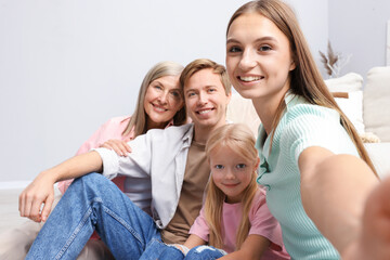 Happy woman taking selfie with her family at home