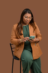Woman in brown blazer using smartphone on brown background