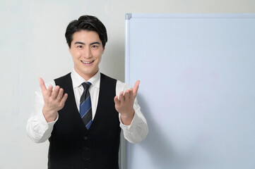 ホワイトボードの前でプレゼンをする日本人男性