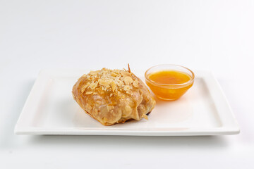 Golden pastry with almond flakes and dipping sauce - sweet moment on white plate