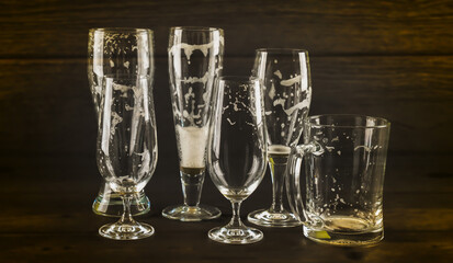 close-up of various empty beer glasses isolated on rustic wooden background indoors in the evening