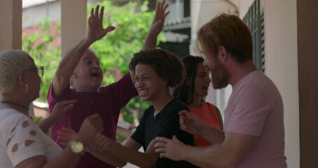 Joyful mixed-age group celebrating with laughter and raised hands on porch, highlighting connection, diversity, and togetherness in a vibrant outdoor social gathering