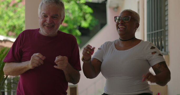 Elderly man and diverse group, including a cheerful Black woman, sharing a joyful dance at a lively outdoor gathering, celebrating inclusion, happiness, and bonding
