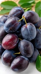 Fototapeta premium Juicy plums stacked together showcasing their deep purple skin and fresh leaves during a sunny harvest season