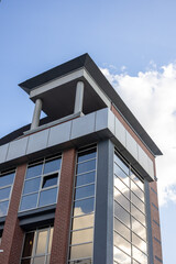 Modern office building with glass facade reflecting sky and clouds. 