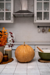A charming autumn kitchen scene with pumpkins, glowing candles, and colorful fall foliage all...