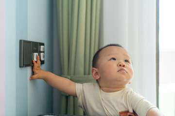A chubby little Asian boy was fascinated by the wall socket, which had been fitted with a safety...