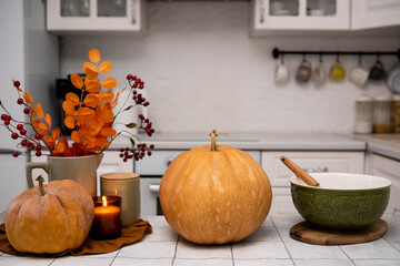 A charming autumn kitchen scene with pumpkins, glowing candles, and colorful fall foliage all around, ceramic bowl for backing.