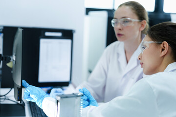 A pharmaceutical Quality Control QC team ensures GxP compliance. Two scientists review an electronic batch record on a tablet while a third performs a required analytical test.