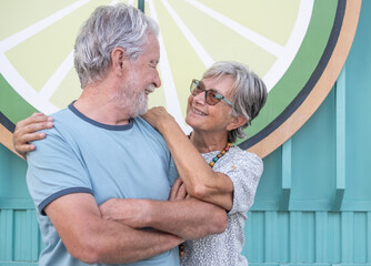 Lovely senior couple hugging smiling standing in outdoors looking at each other happily expressing love and emotions. Youthful couple enjoying retirement lifestyle