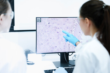 A pharmaceutical Quality Control QC team ensures GxP compliance. Two scientists review an electronic batch record on a tablet while a third performs a required analytical test.