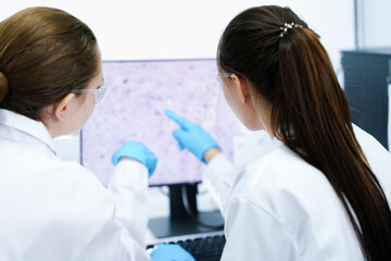 A pharmaceutical Quality Control QC team ensures GxP compliance. Two scientists review an electronic batch record on a tablet while a third performs a required analytical test.