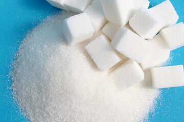 There are cubes of refined sugar lying on a pile of granulated sugar.	