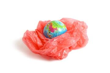 On a white background lies a model of the earth in a red plastic bag.