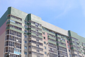 Naklejka premium A high-rise multi-storey brick house stands against a blue sky, photo from bottom to top. 
