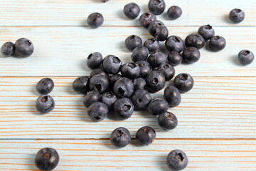 Scattered blueberries lie on a wooden table.