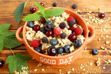 A white bowl of muesli with berries stands on a wooden table.