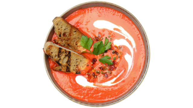 Creamy red soup with grilled bread and parsley garnish
