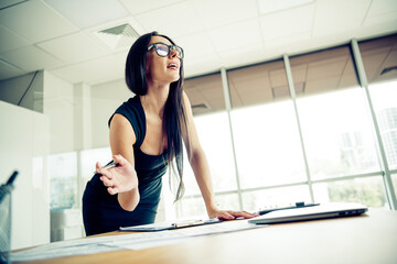 Confident businesswoman in professional attire gestures enthusiastically during a meeting in a modern office setting
