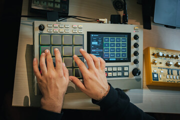 The hands of an artist creating music with his drum machine MPC LIVE II