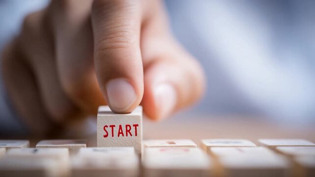 Initiation's Touch: A focused hand delicately presses a wooden block marked START, symbolizing the pivotal moment of beginning, action, and seizing the opportunities that await.