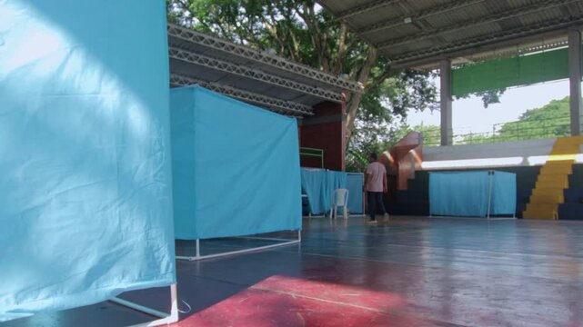 Portable blue cubicles set up inside a gymnasium for a rural community medical outreach event, offering free healthcare services by volunteer professionals in Colombia.