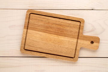 Kitchen wooden board on a wooden table, close-up, top view.