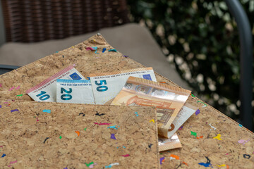 Euro banknotes, including 10, 20, 50, and 5 Euro notes, are displayed in a modern cork wallet,...