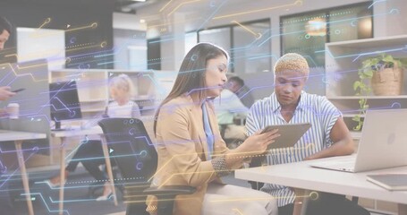 Business women pointing tablet showing circuit chart overlay while male peer walking checking phone - Powered by Adobe
