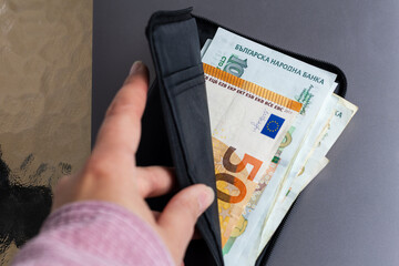 Hand opens wallet, revealing Bulgarian Lev and Euro banknotes. Highlights Bulgaria's economic...