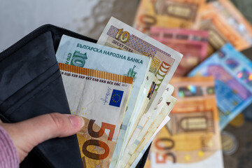 Bulgarian Lev and Euro banknotes in a wallet, symbolizing Bulgaria's financial shift towards Euro adoption. © VikSid