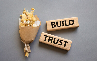 Build trust symbol. Wooden blocks with words Build trust. Beautiful grey background with bouquet of flowers. Business and Build trust concept. Copy space.