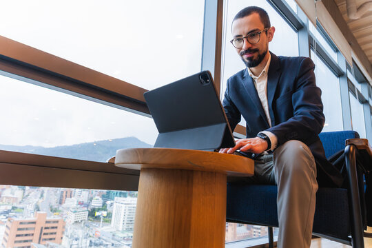 Young professional using tablet by office window working remotely