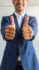 photo of a businessman in suit showing double thumbs up gesture with blurred background