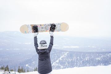 A girl lifted a snowboard to the top of a mountain