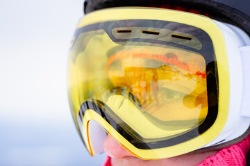 A close-up of a pair of yellow ski goggles worn by a person