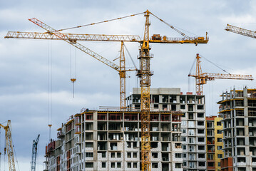 Tower cranes lifting materials over an urban construction site as residential and commercial buildings rise, symbolizing infrastructure growth, development and future progress
