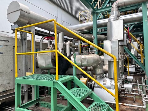 Close-up view of industrial steel pipelines, valves, and structural support in a modern chemical or petroleum refinery plant. Detailed view of industrial equipment and machinery with a warning sign fo