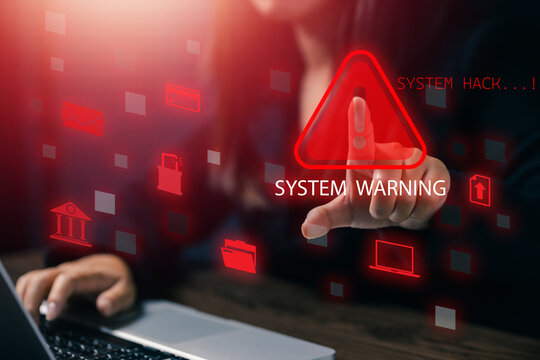 A woman pointing to a glowing red system warning sign on her laptop, representing cyber attack, data breach, security alert, and computer system hacking detection warning concept.