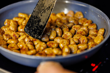 Sizzling chicken sausage cooking in a pan with spatula ready for eating