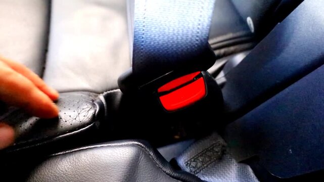​A hand inserts a seat belt into the buckle, securing it with a click. This serves as a reminder of the importance of safety on the road.