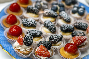 Christmas pastries decorated with powdered sugar and fresh strawberries and blackberries on vintage blue plate.